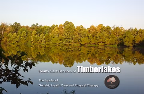 Tranquil lake reflects a tree-lined shore beside Timberlakes Health Care Services.