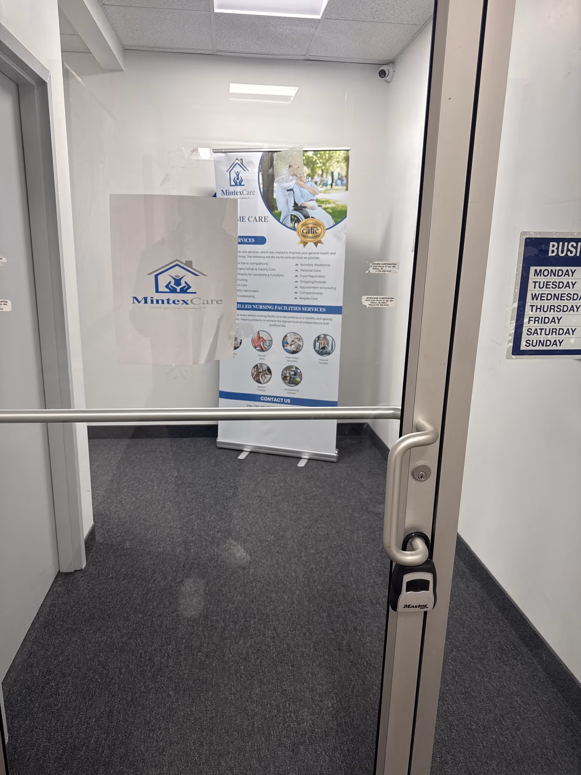 Interior corridor with a MintexCare banner, glass door, and carpeted floor in a senior facility.