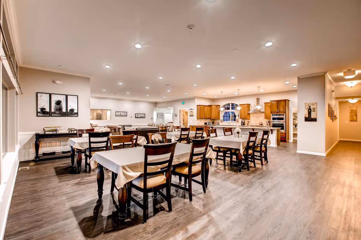 Spacious dining room in a senior living facility with tables, chairs, and a kitchen island.