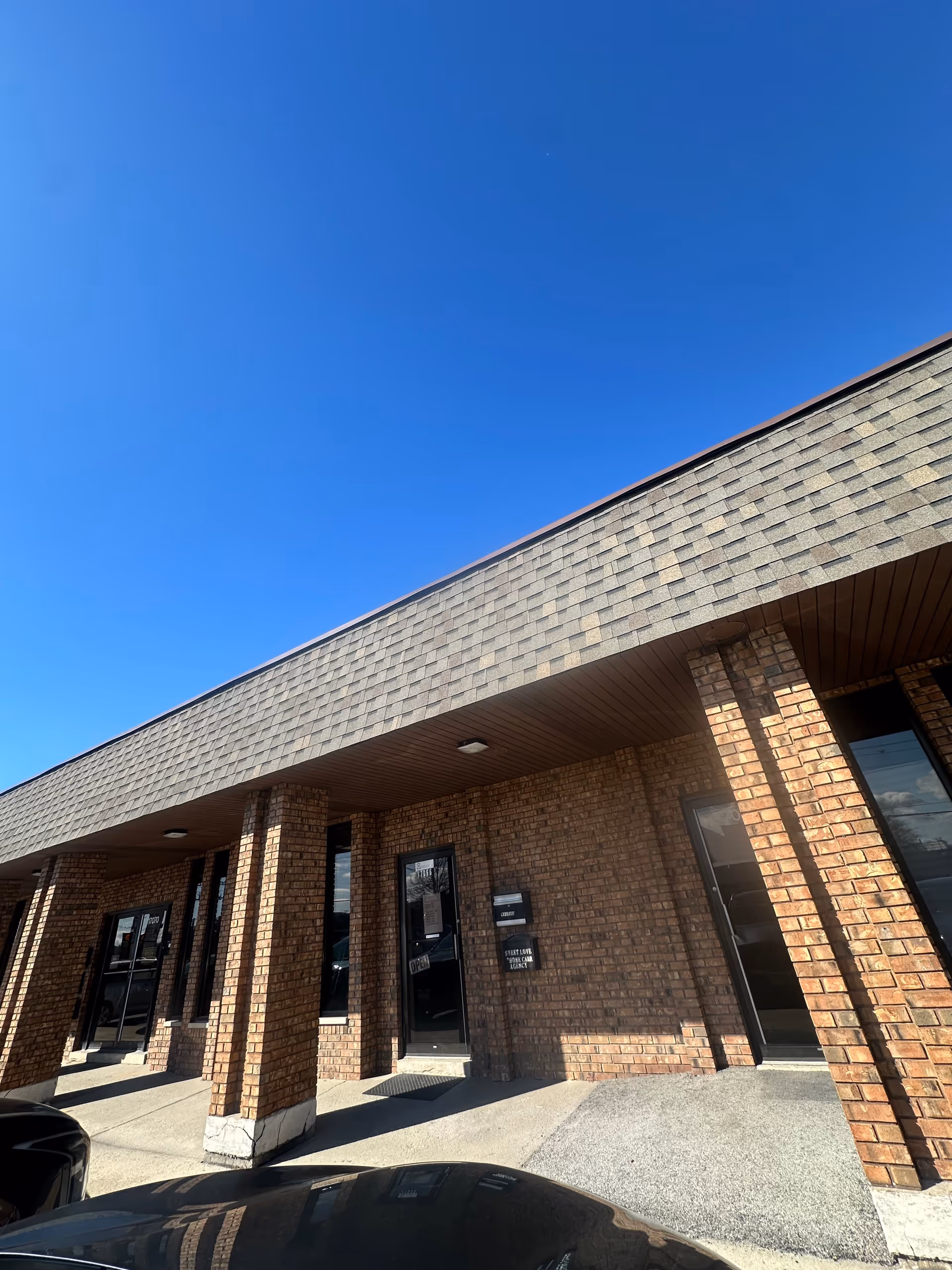 Brick storefront with pillars and glass doors under a sloped roof.