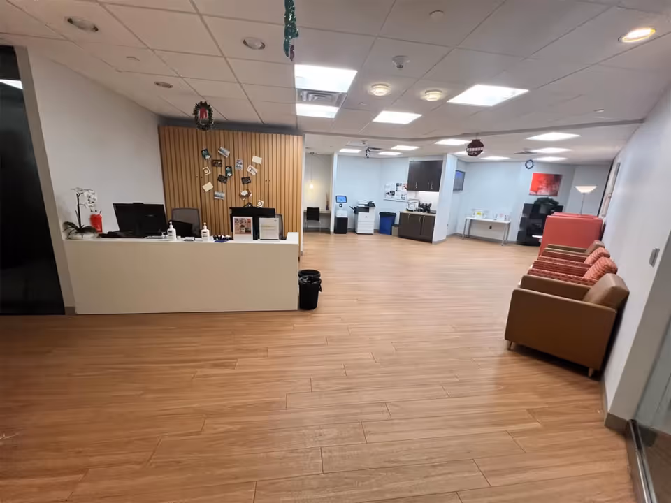 A reception desk with computers and chairs in a spacious senior living lobby.