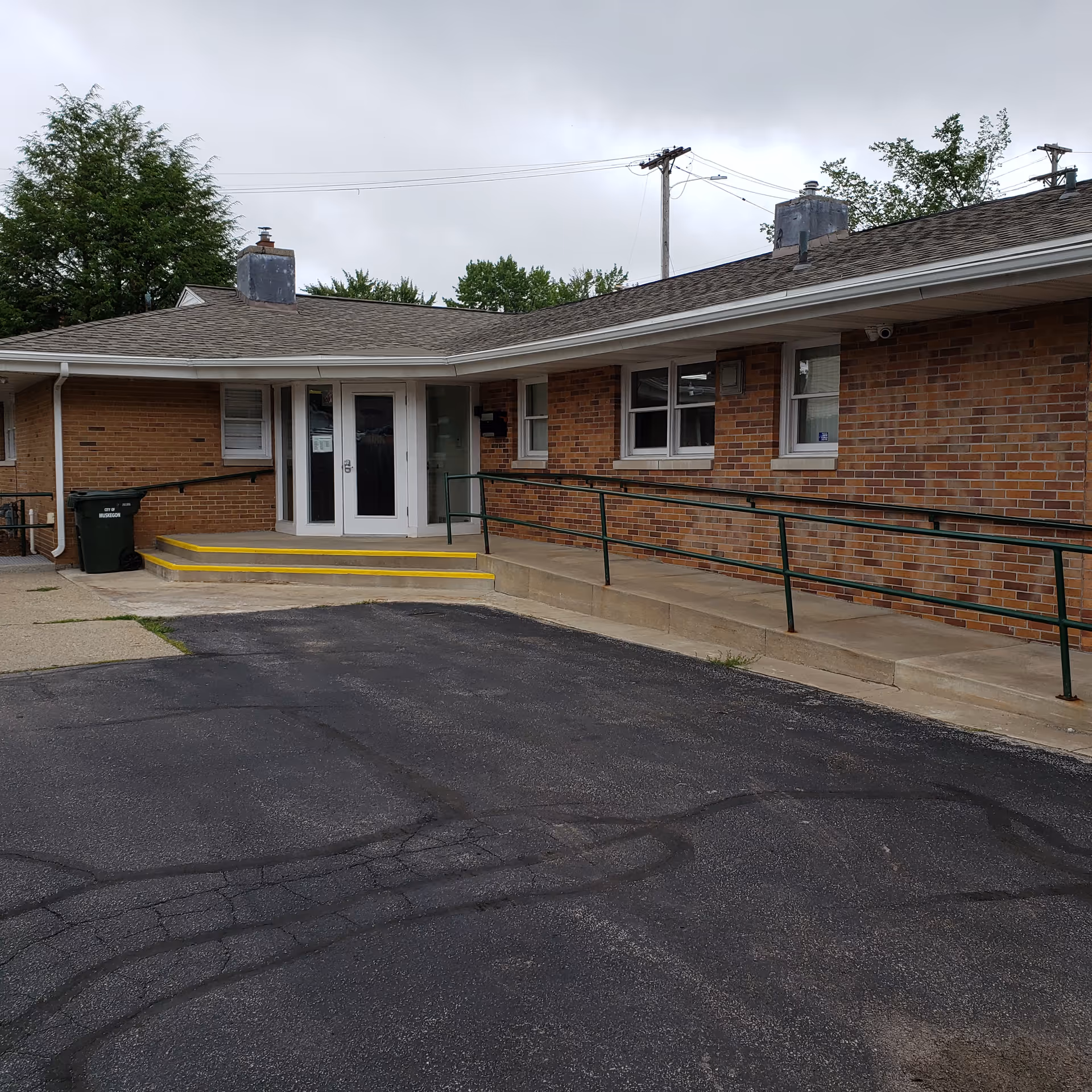 Single-story brick senior facility entrance with glass doors and a ramp.