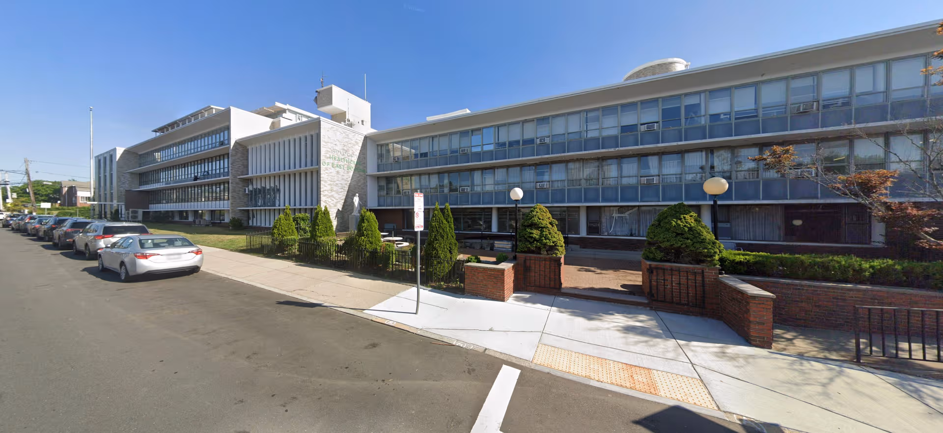 Exterior view of a modern Advocate Healthcare building in East Boston with parked cars