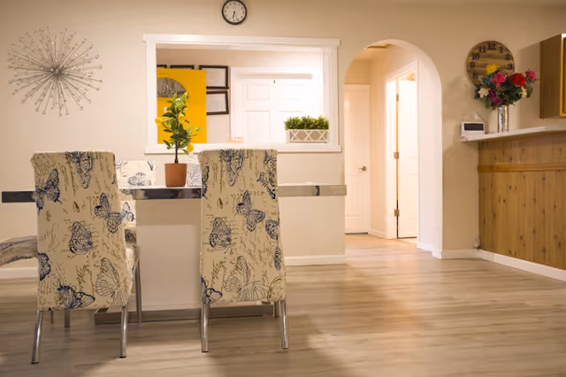 Interior dining area with butterfly-pattern chairs around a table and an archway.