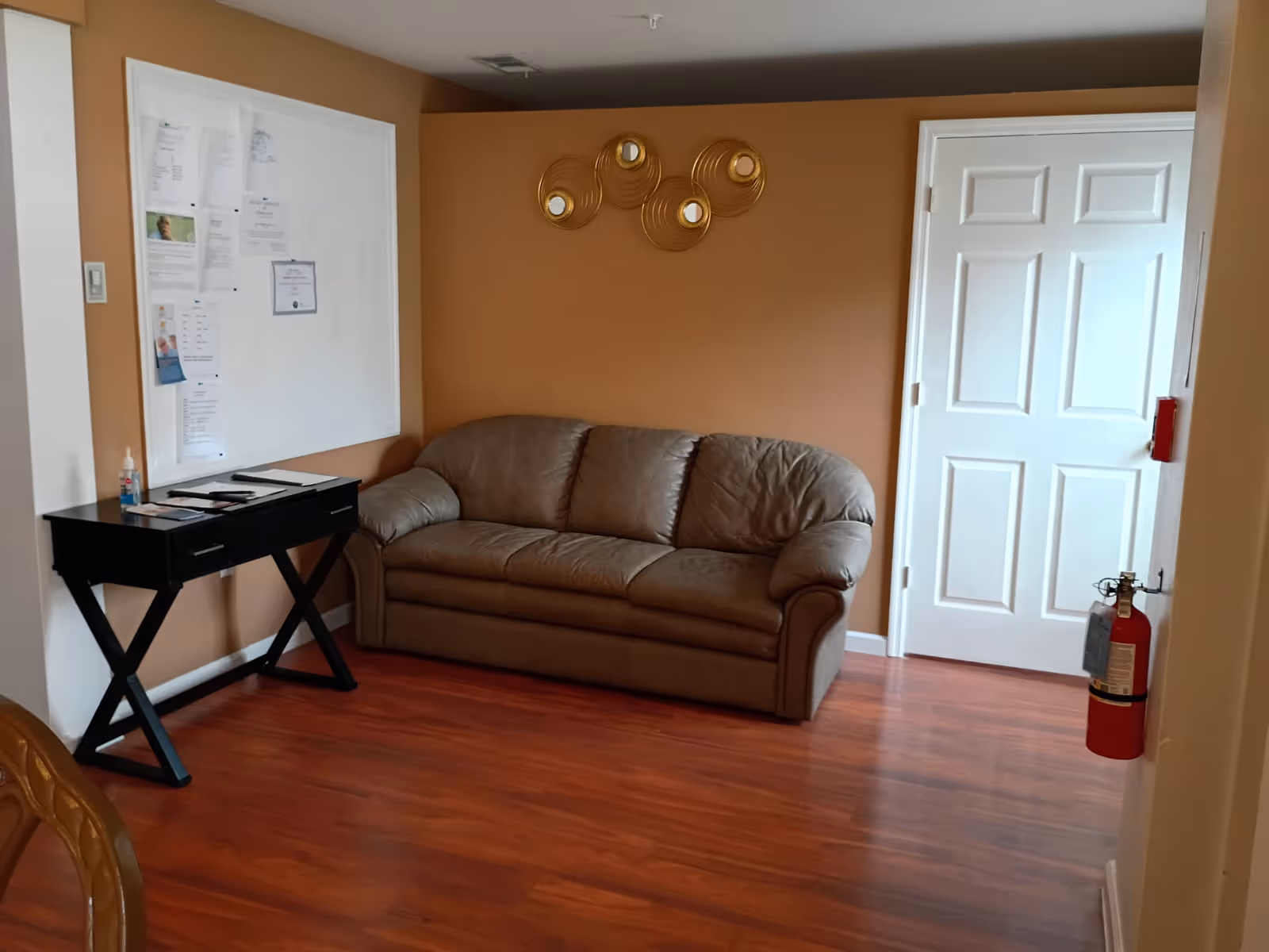 Brown leather sofa against an orange wall in a small facility lounge.