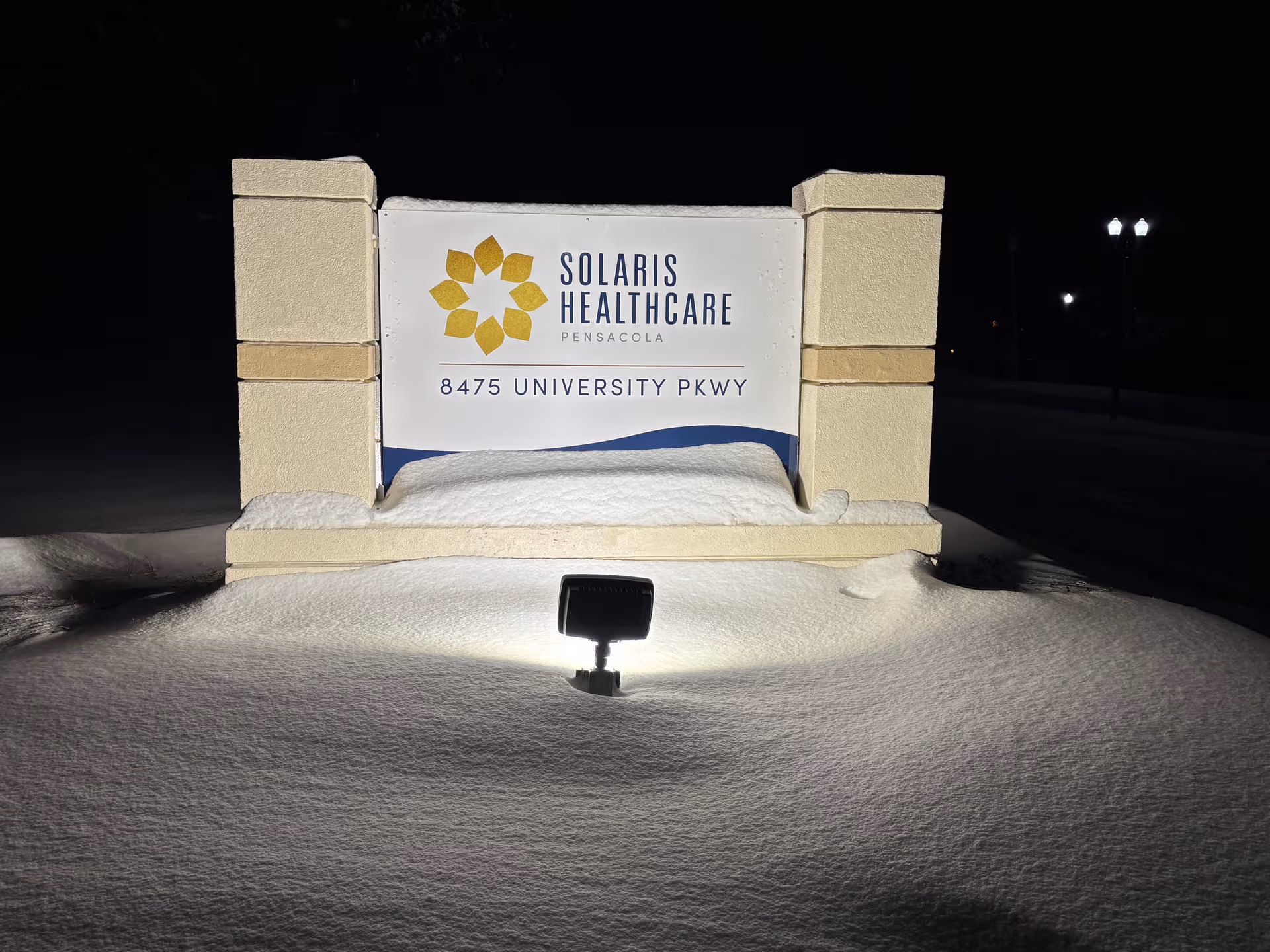 Night view of Solaris HealthCare Pensacola entrance sign illuminated by ground light.