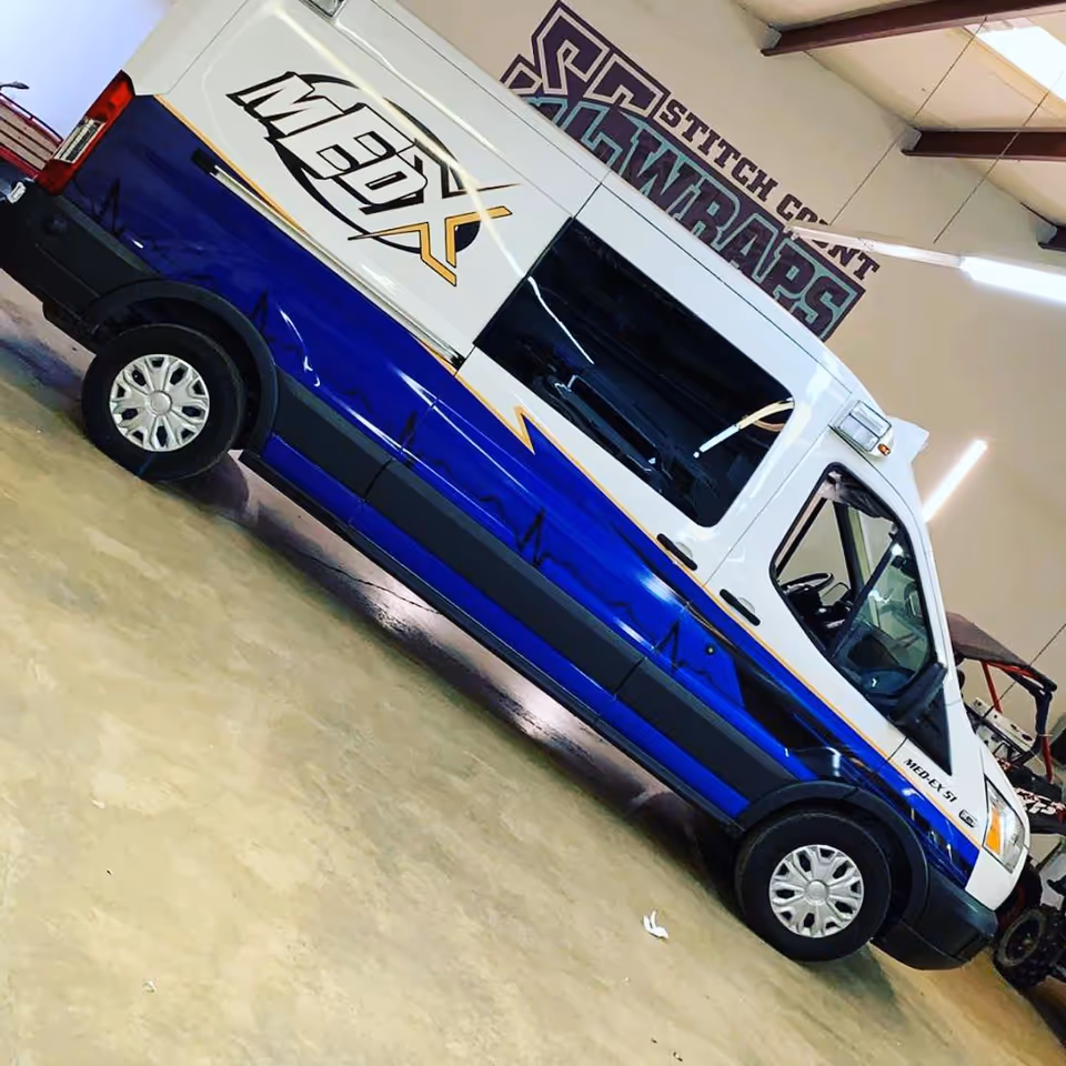 Blue and white MedEx medical transport van parked indoors inside a facility bay.