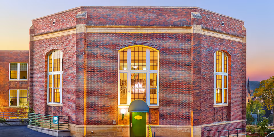 Brick senior living facility exterior with tall arched windows and a green entrance door.