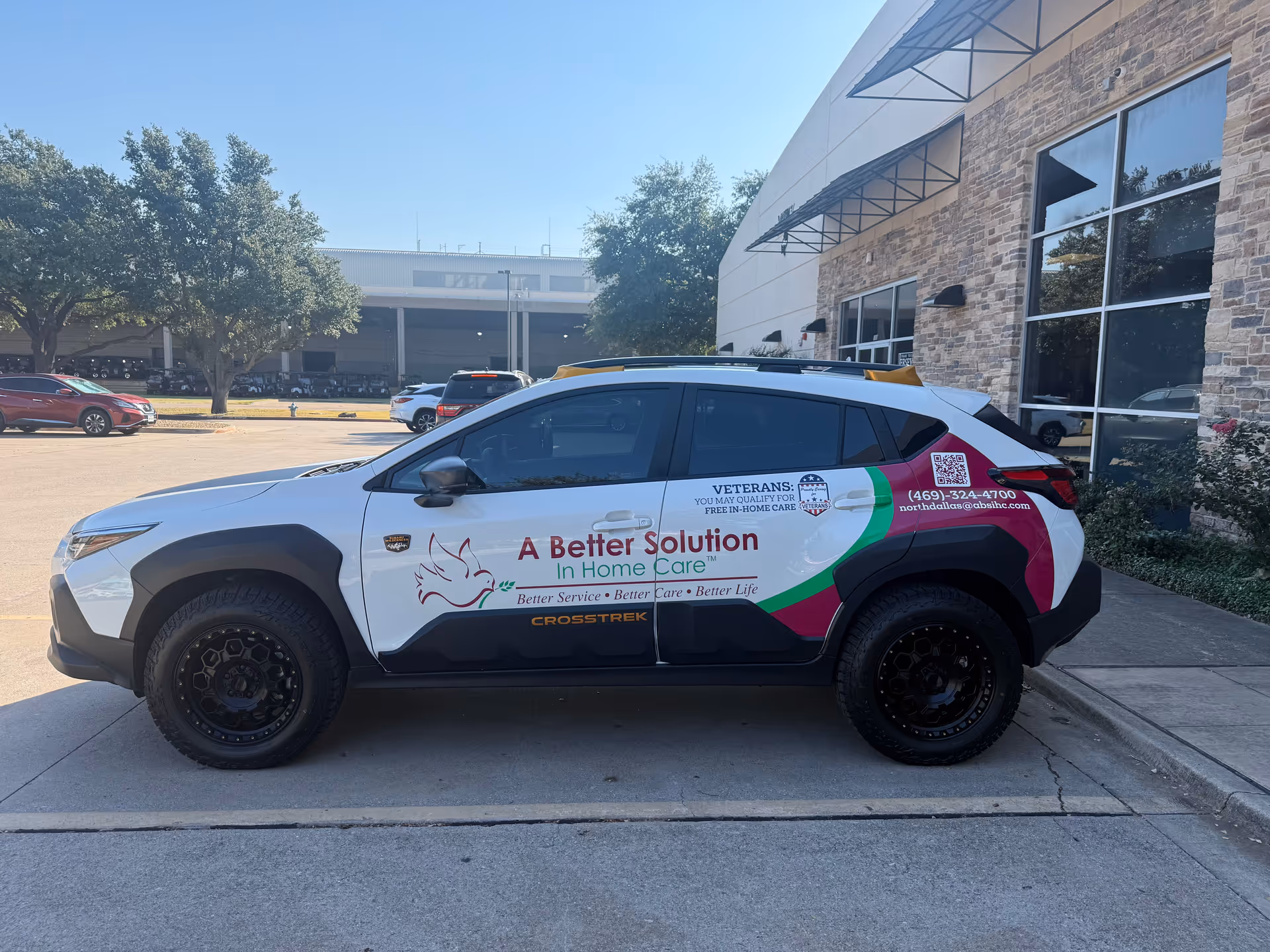 Promotional vehicle for A Better Solution In Home Care parked outside a modern facility.