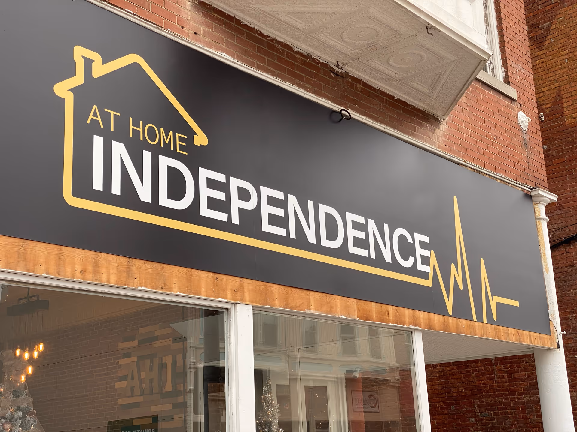 Exterior storefront sign reads AT HOME INDEPENDENCE with a yellow house outline logo.
