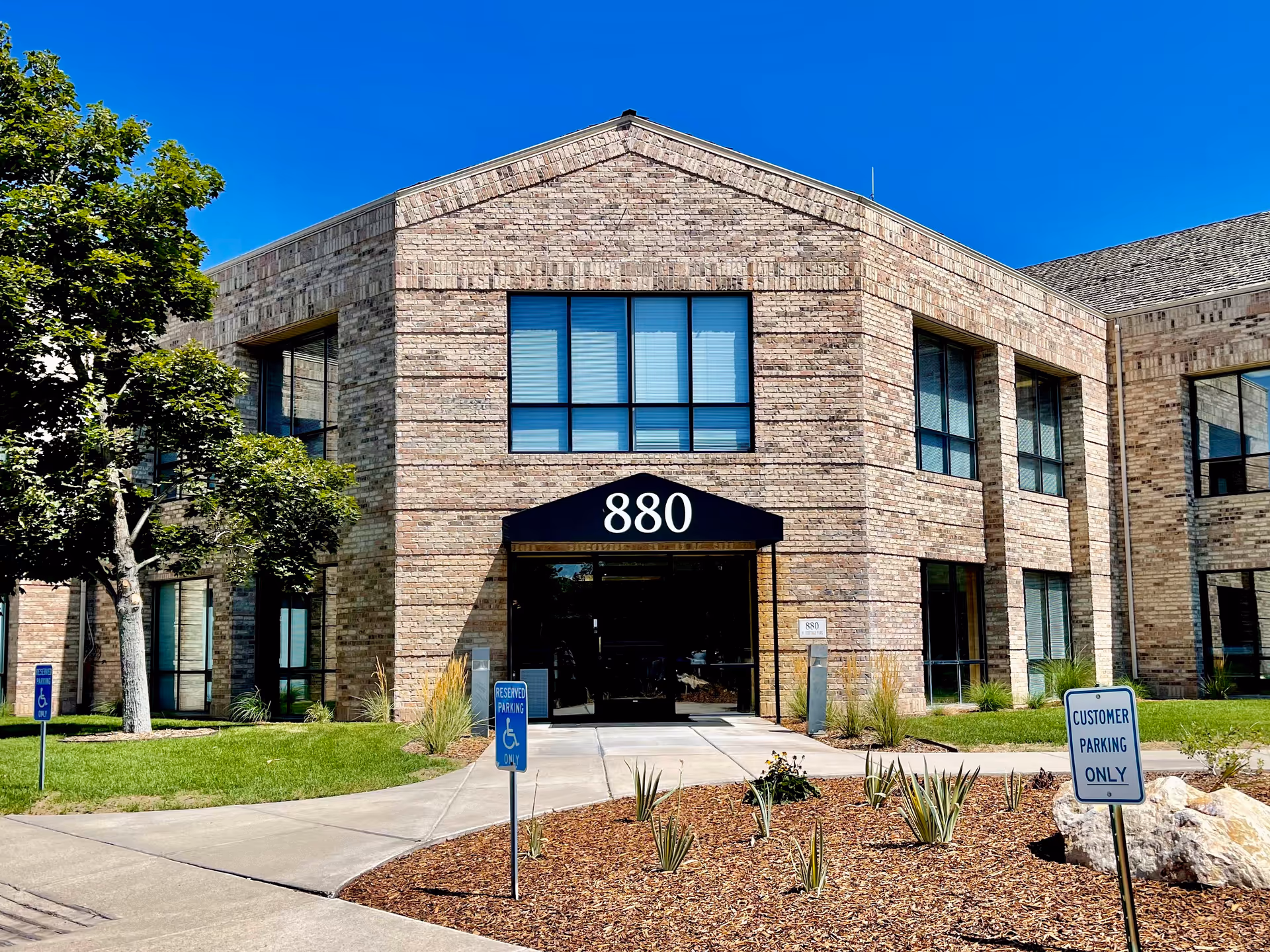 Brick senior living facility entrance with black awning marked 880, handicap parking signs visible.