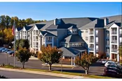 Exterior view of a multi-story senior living building with trees and parked cars.