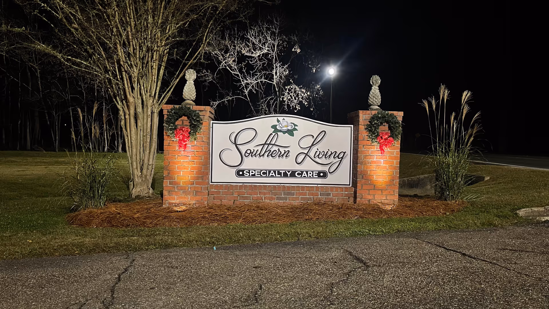 Nighttime view of the Southern Living Specialty Care sign on brick entrance pillars.