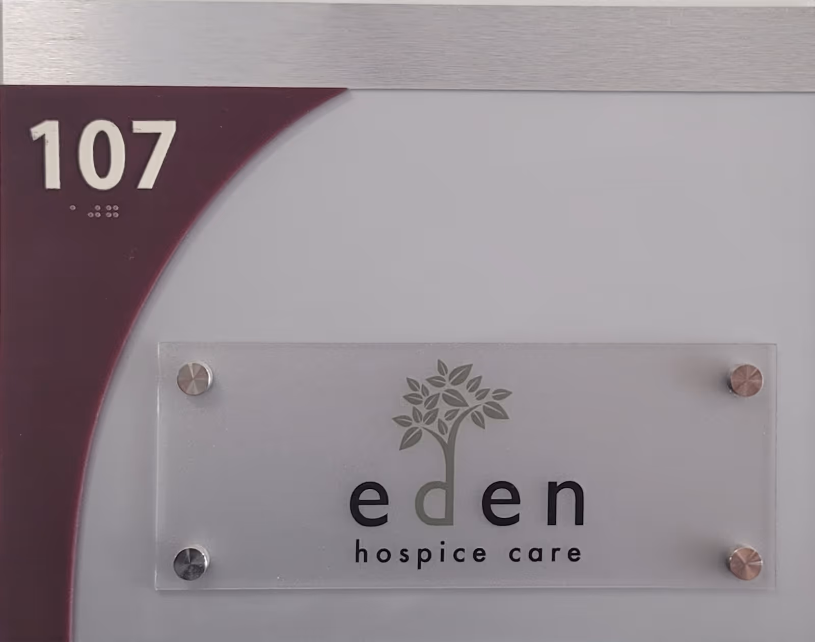 Room 107 signage for Eden Hospice Care mounted on a wall panel.