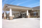 Exterior view of Spurgeon Manor entrance with a covered drop-off area and brick pillars.