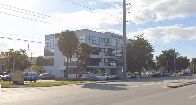 Exterior view of Care Pro D and D Inc building along a street with palm trees.