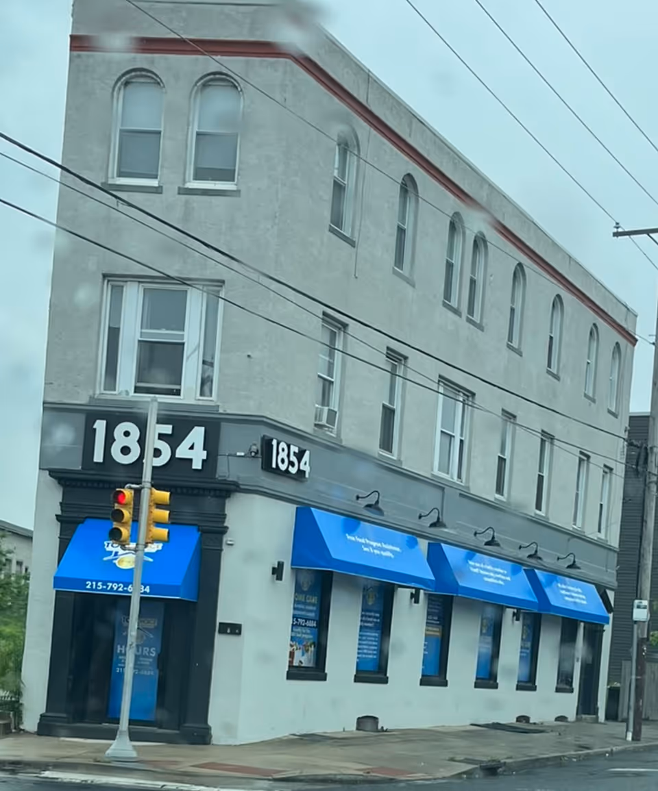 Two-story building with blue storefront awnings and the address 1854