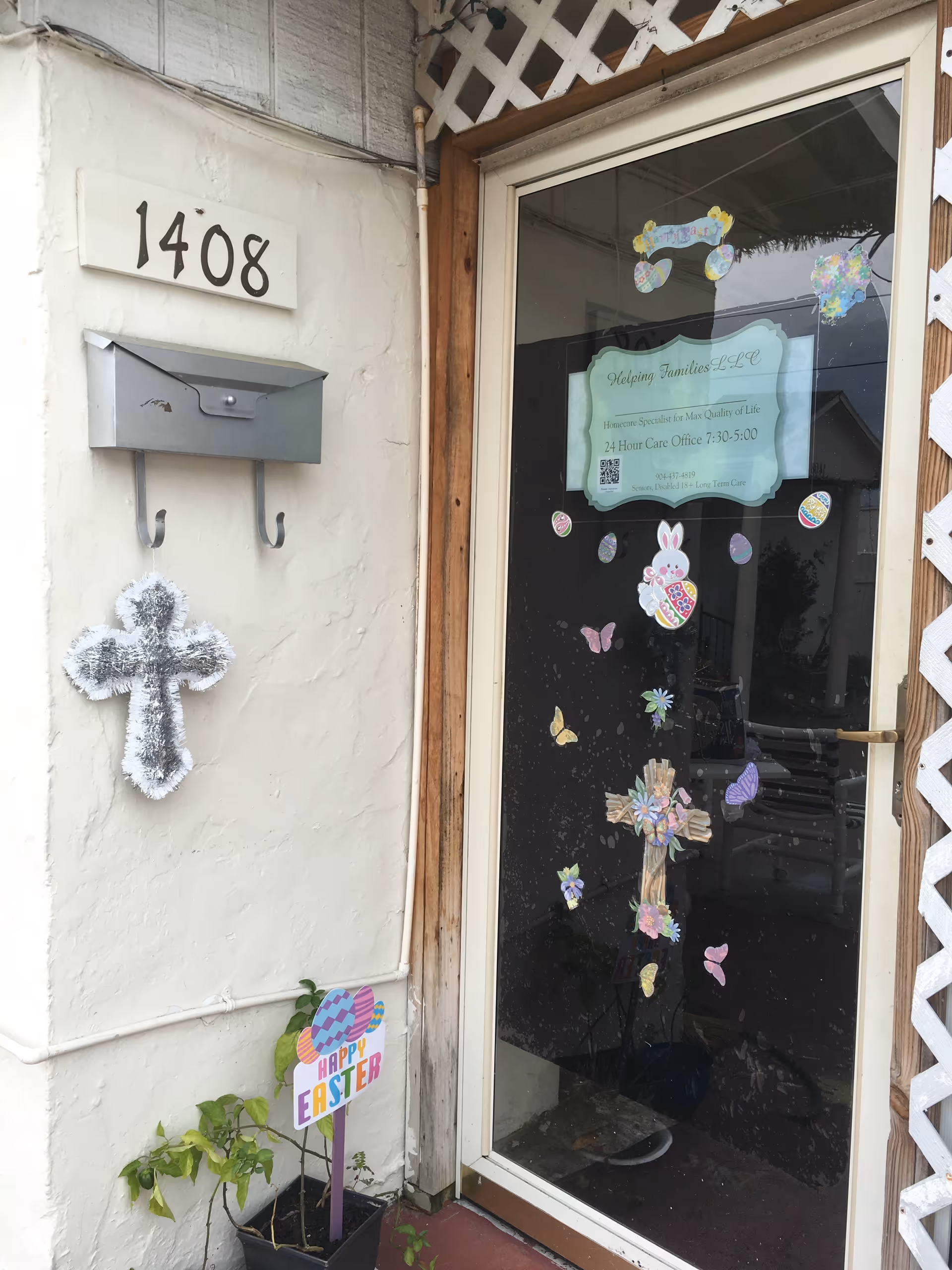 Exterior entrance with glass door, address 1408, Easter decorations, and cross on wall.