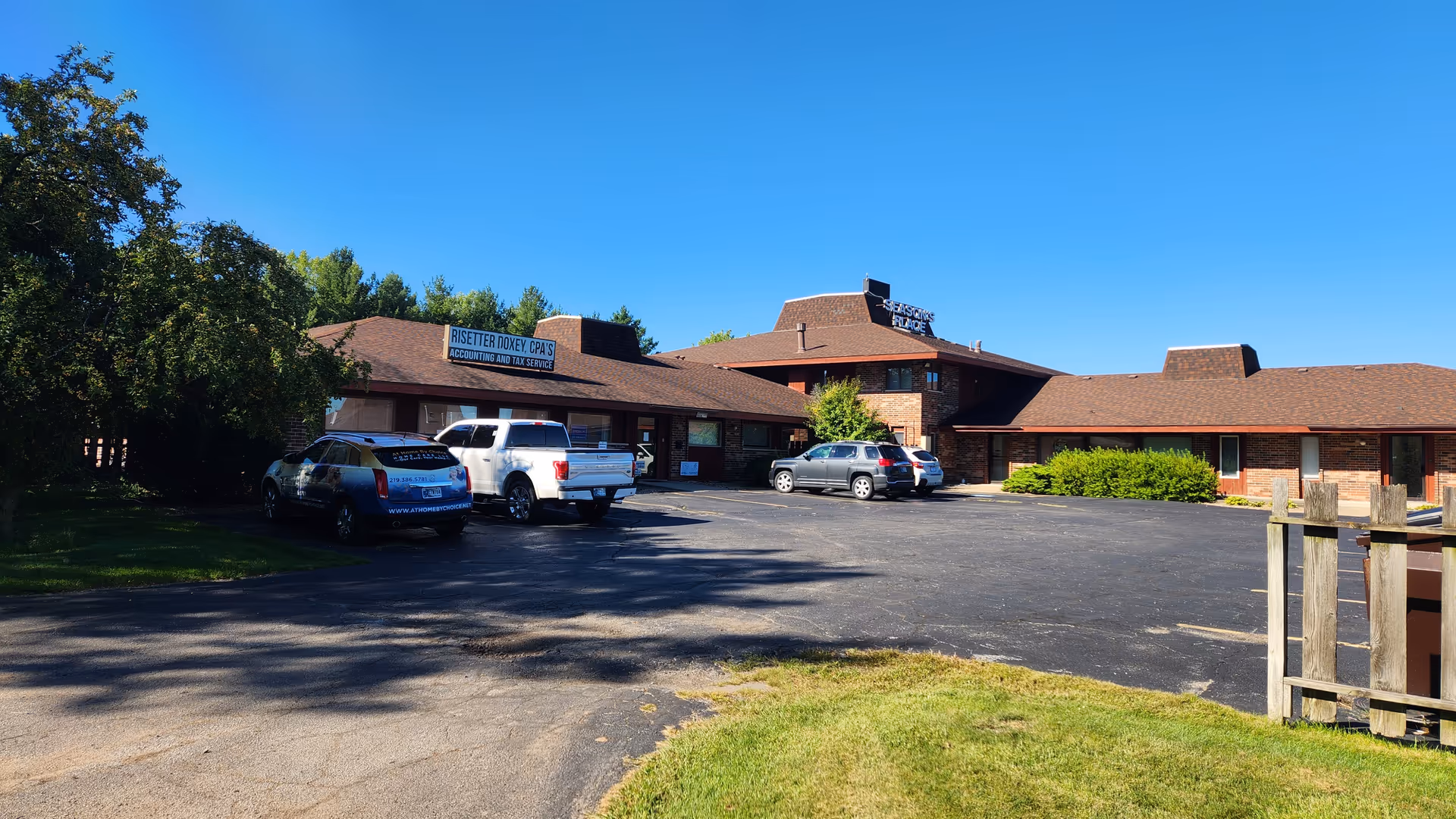 Exterior view of a brick senior care building with parked cars in lot