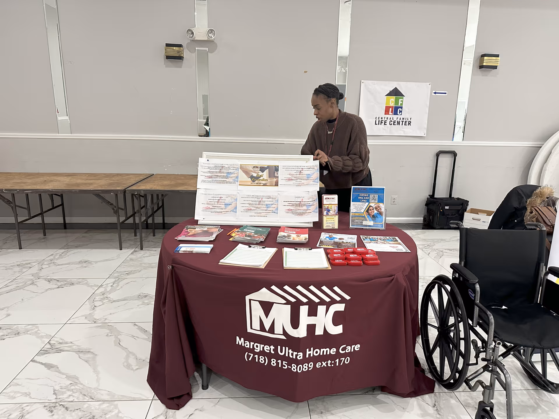 Staff member behind a maroon information table in a senior care facility lobby.
