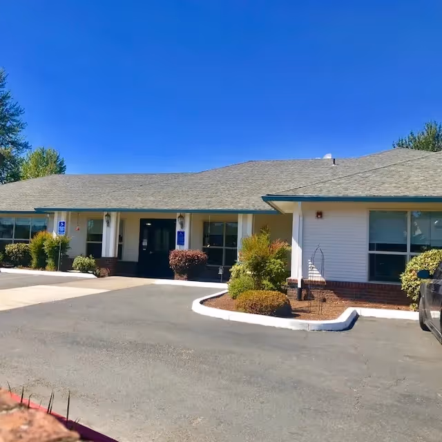 Front exterior of a single-story senior housing facility with entry doors and landscaping.