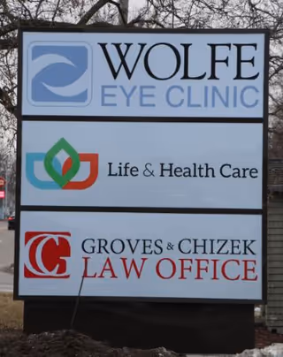 Exterior signboard showing Wolf Eye Clinic, Life & Health Care, and Groves & Chizek Law Office.