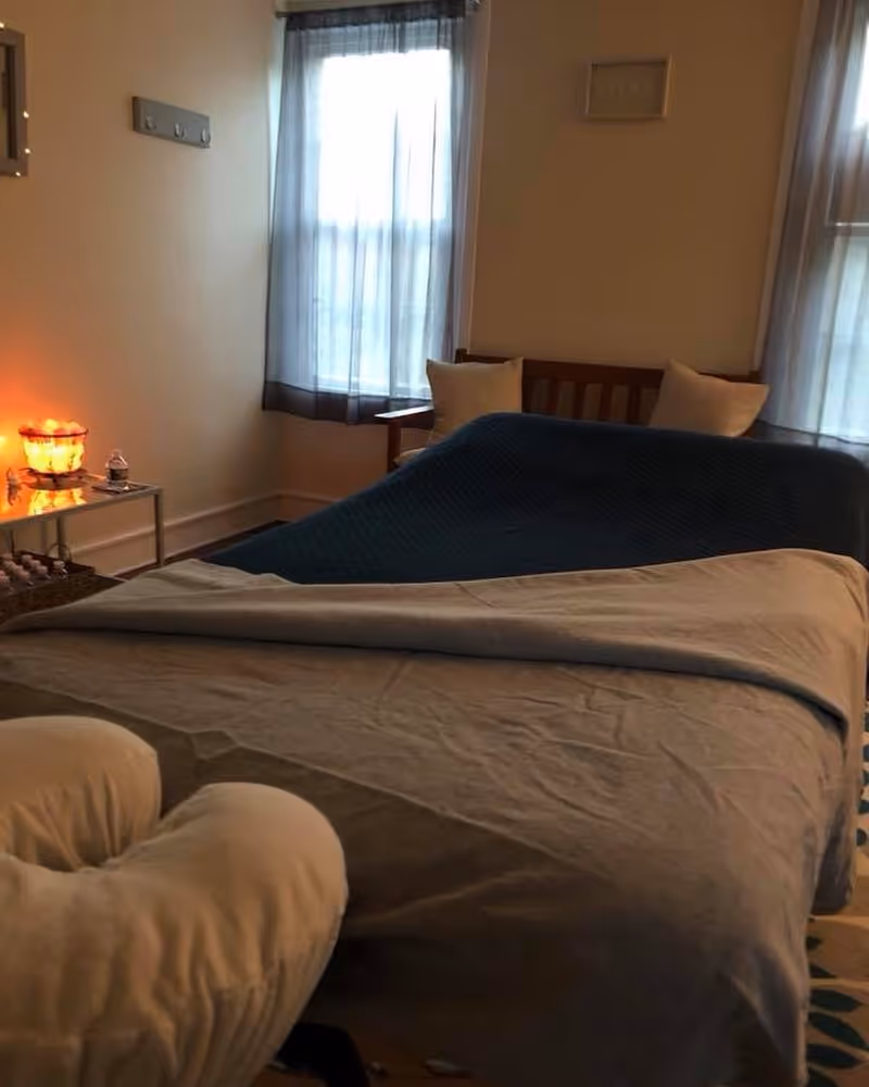 A cozy senior facility bedroom with a bed, nightstand, and glowing lamp.