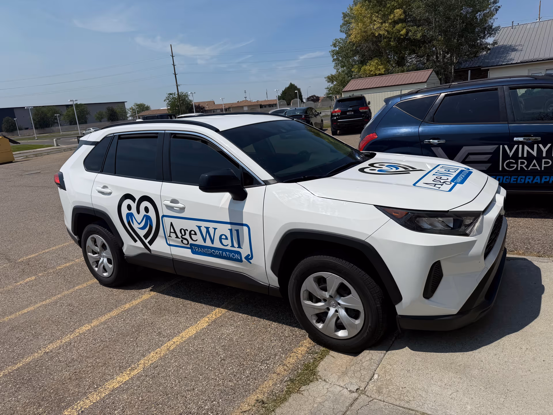 White AgeWell Transportation SUV parked in a lot beside a facility, branding visible