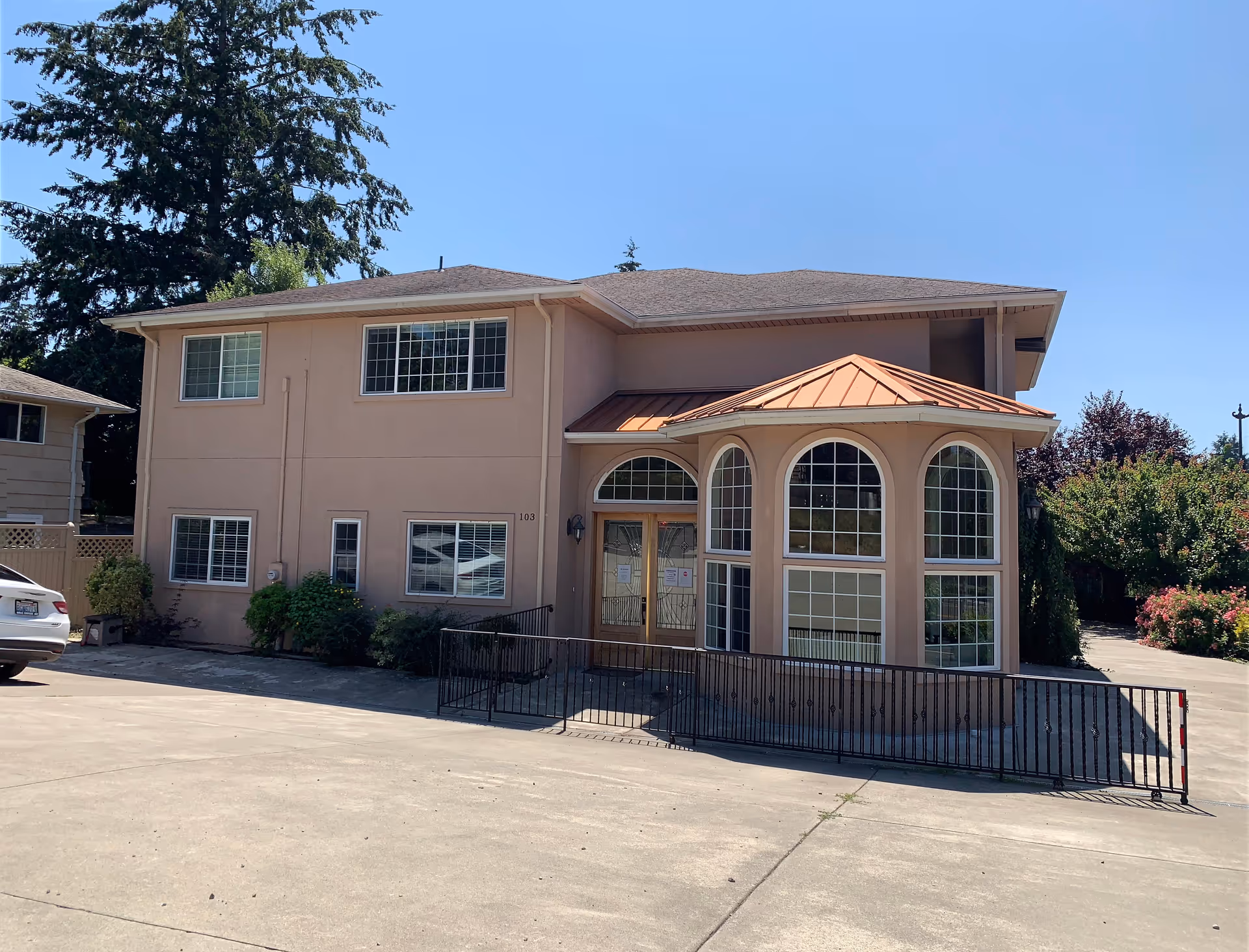 Two-story beige senior living facility with arched windows and a wheelchair ramp.