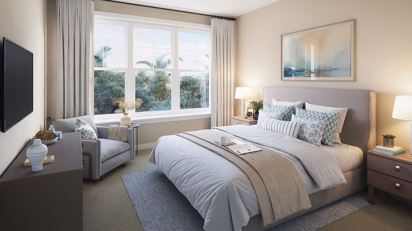 Bright, neatly staged bedroom with a large bed, armchair by a big window, nightstands and a wall-mounted TV.
