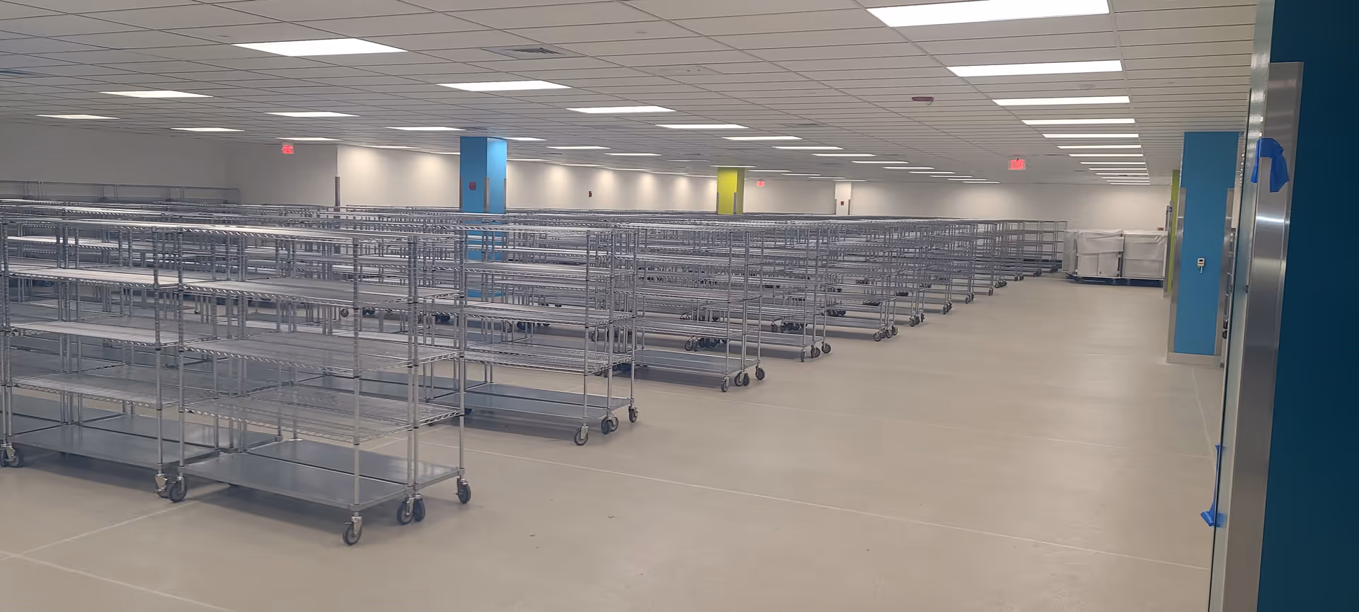 A spacious empty utility room with rows of metal rolling carts.