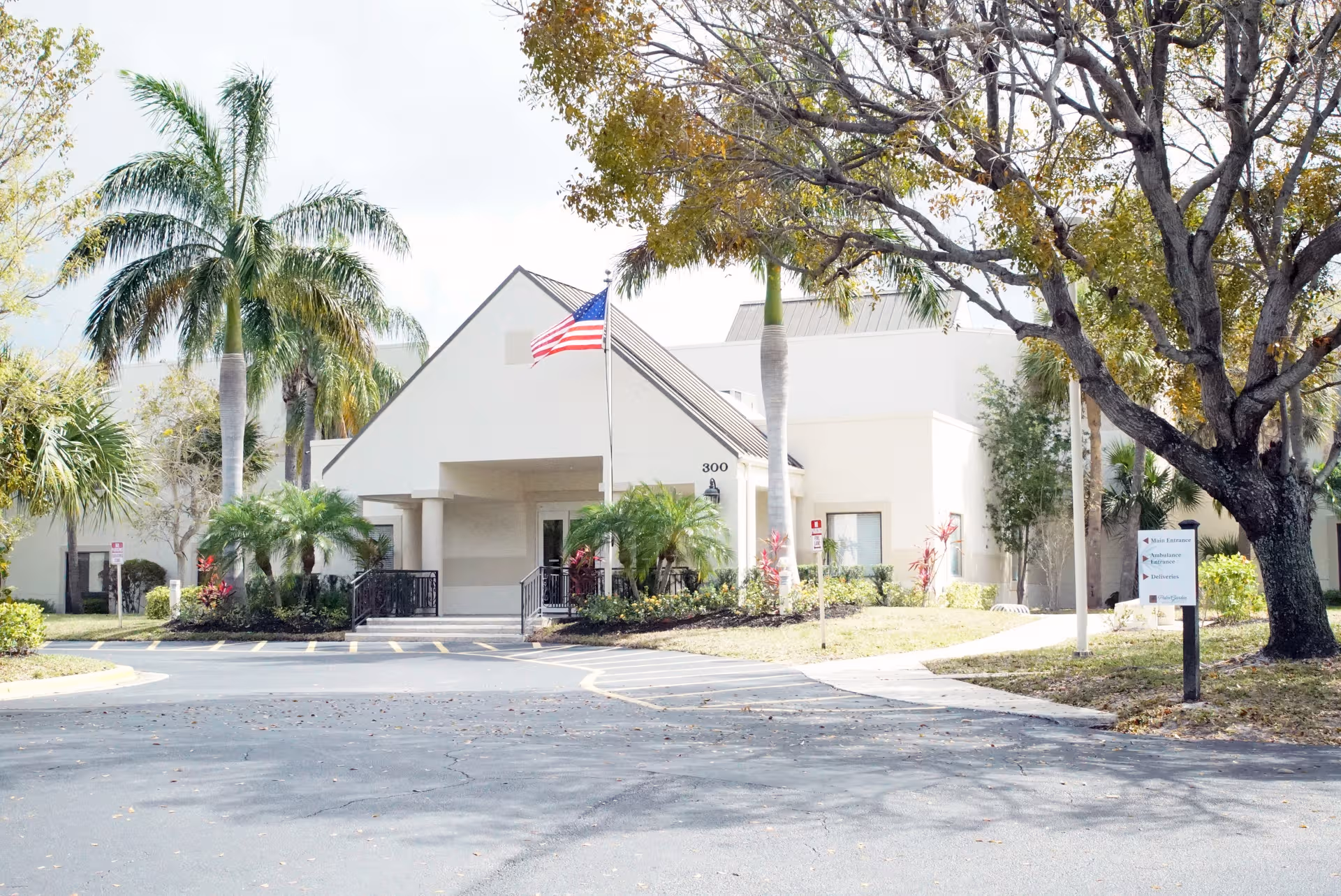 Palm Garden of West Palm Beach exterior with white entrance and palm trees.