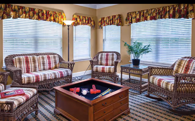 Wicker lounge chairs with plaid cushions surround a central wooden game table.