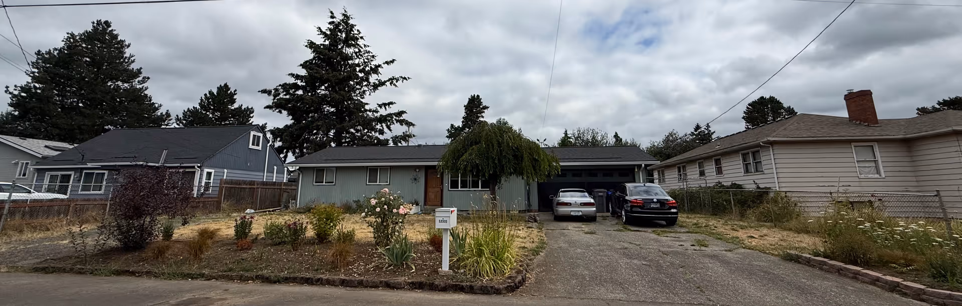 Row of single-story homes along a street with cars parked in driveways.