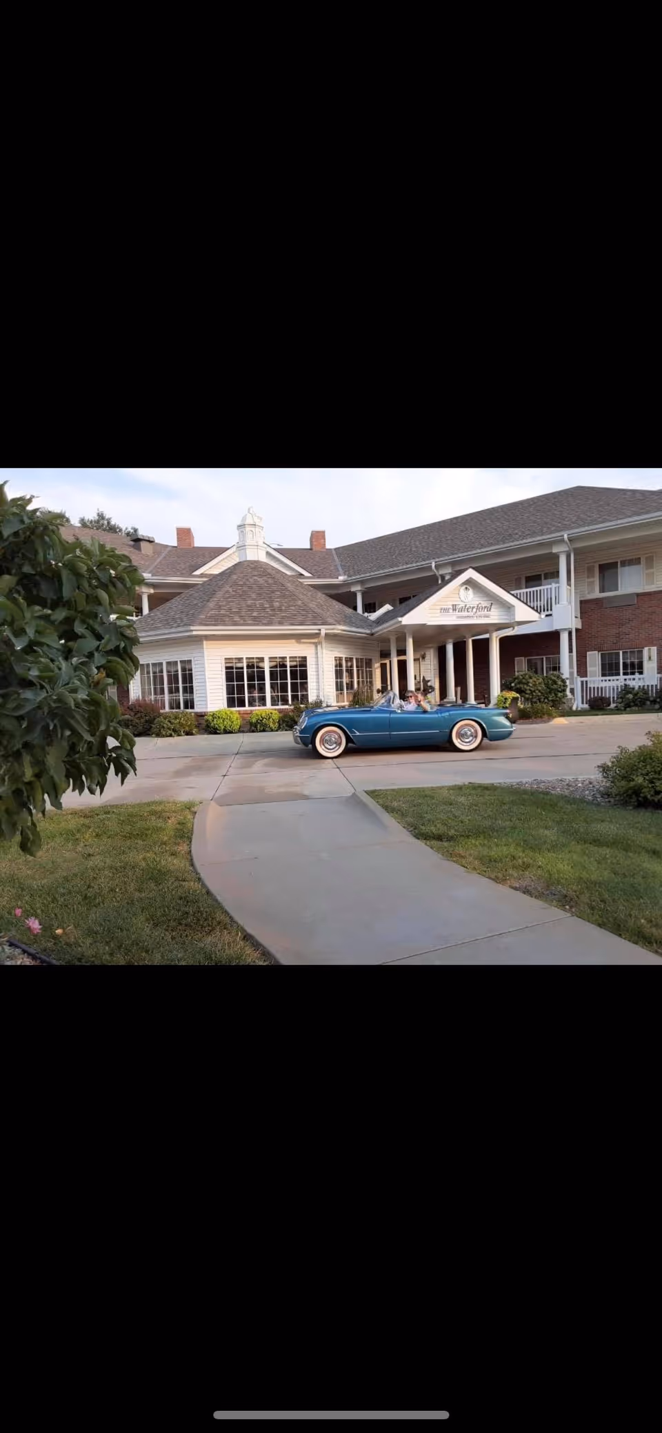 Exterior view of Waterford at Wilderness Hills front entrance with a vintage blue convertible.