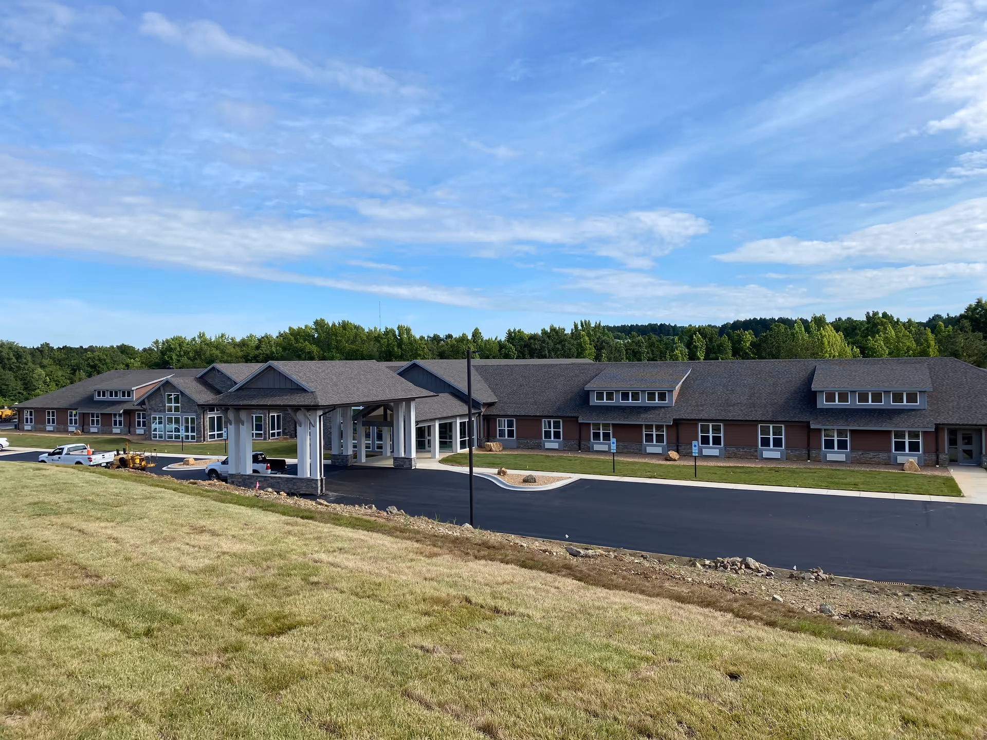 Exterior view of The Drake senior living facility with a long brick building and driveway.