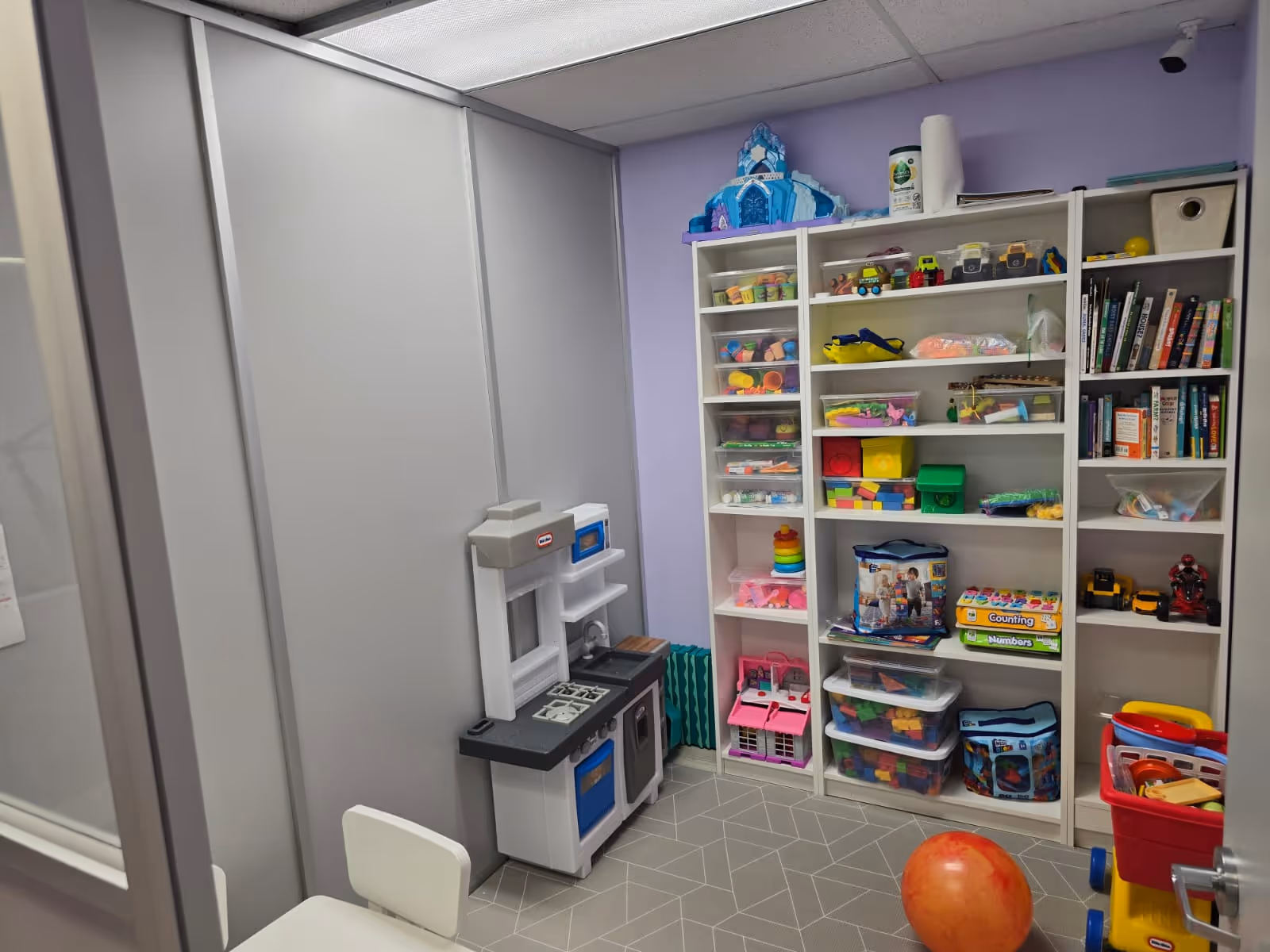 Small playroom with toy shelves, a kid-sized kitchen, and colorful children's toys