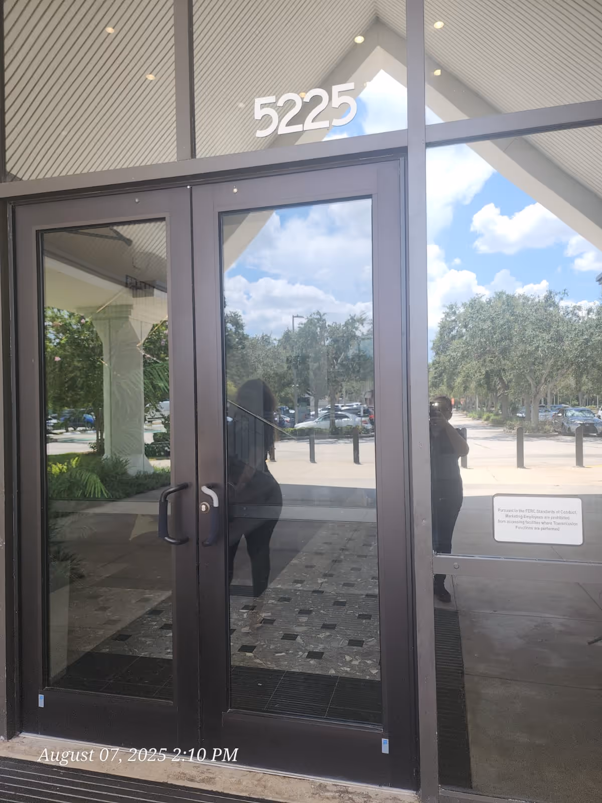 Glass entrance doors with 5225 visible, reflecting trees and parked cars outside.