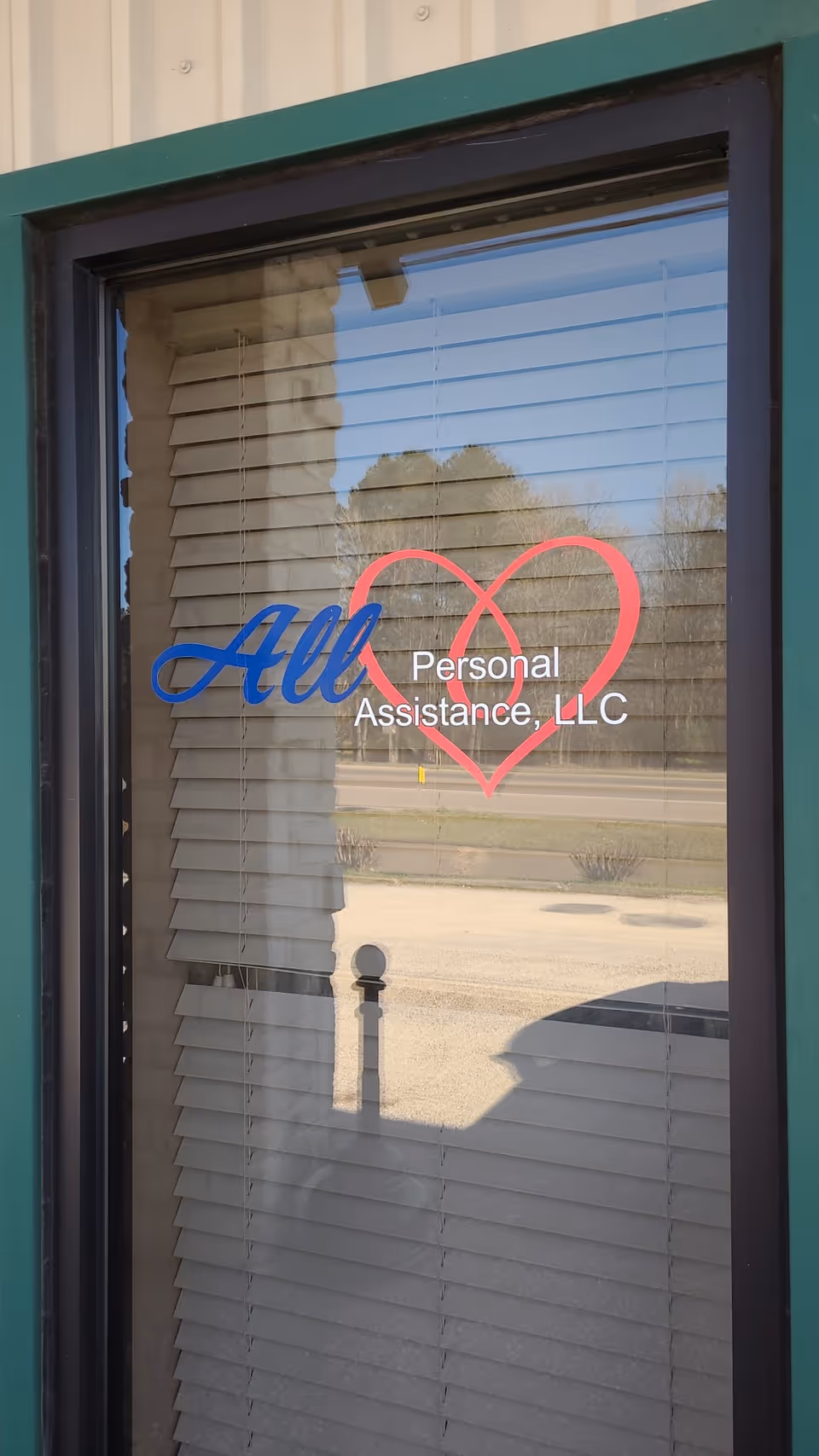 Glass door with blinds showing All Personal Assistance, LLC and a pink heart logo