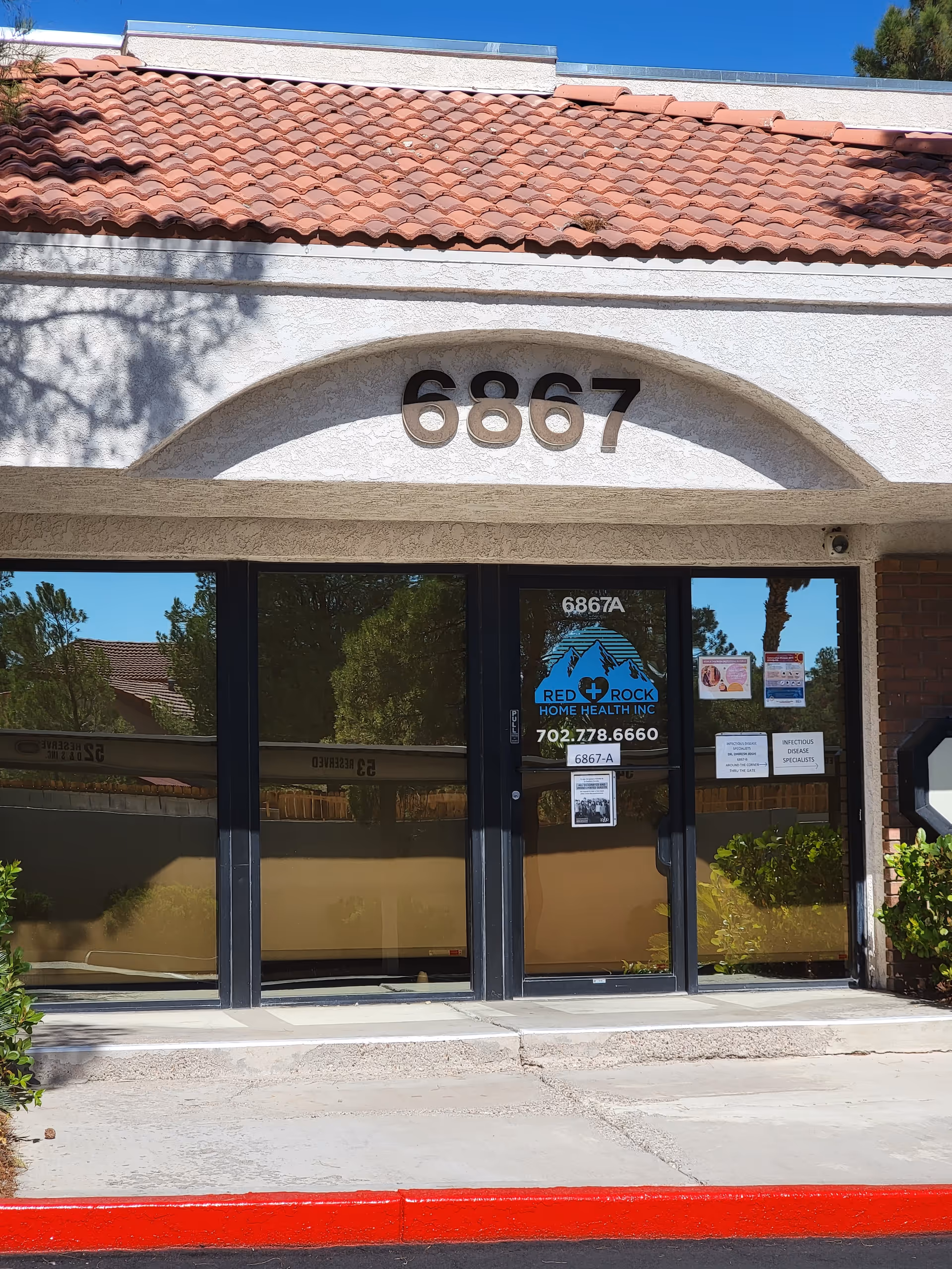 Front of a building with address 6867, glass doors, and a Red Rock Home Health sign.