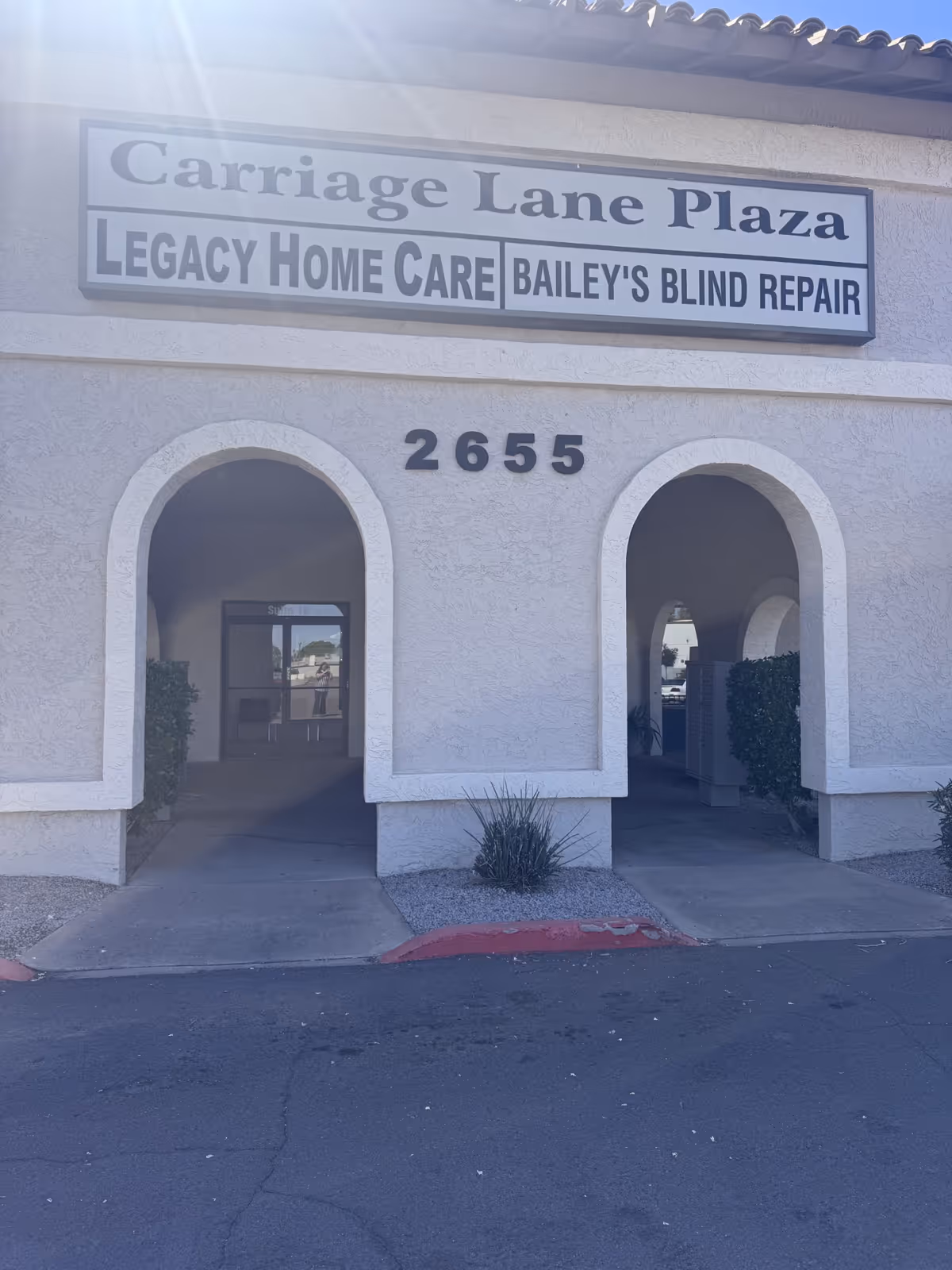 Front view of a beige building with arched entrances and a Carriage Lane Plaza sign.