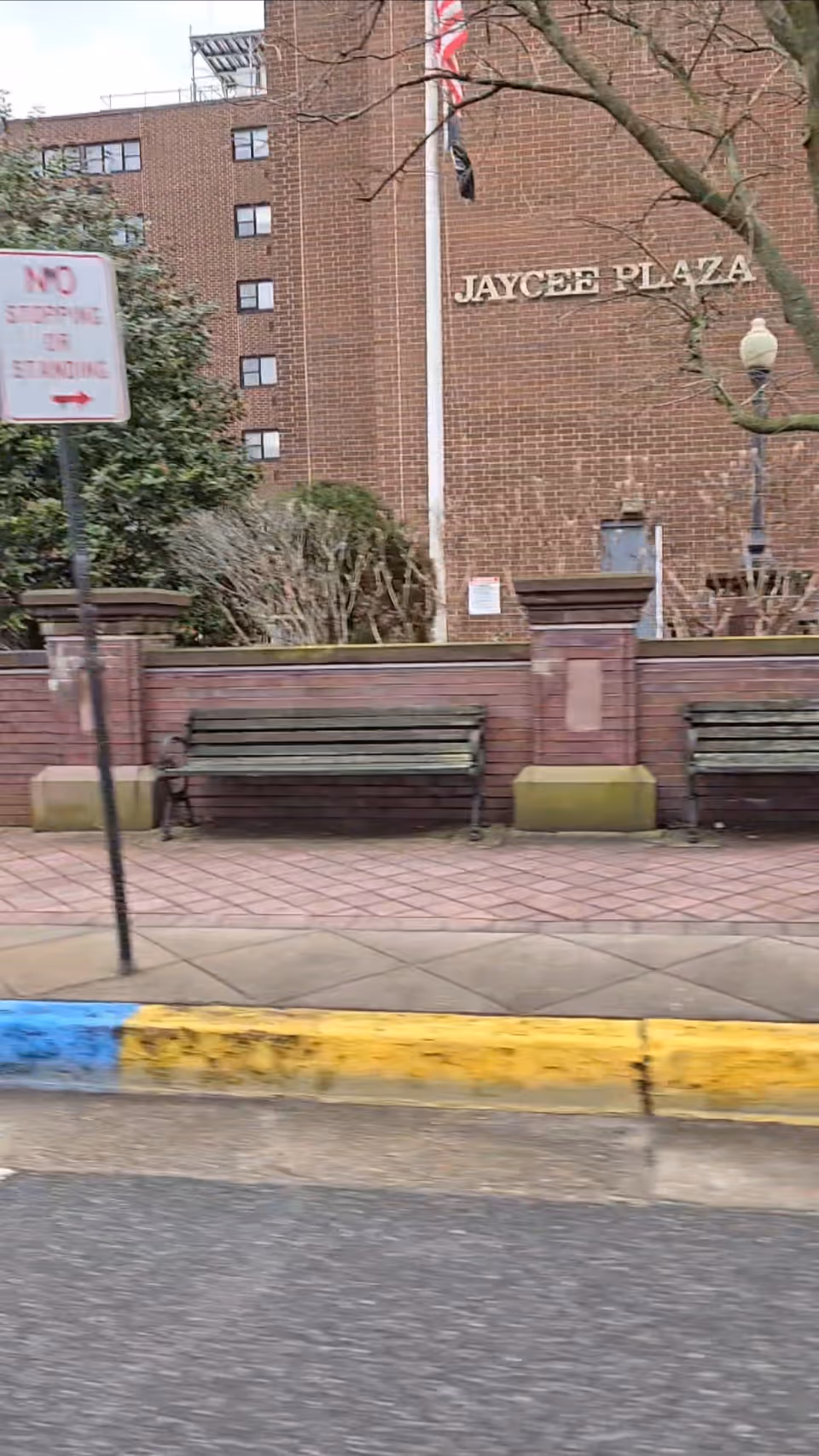 Front exterior view of Jaycee Plaza Assisted Living with benches along brick building.