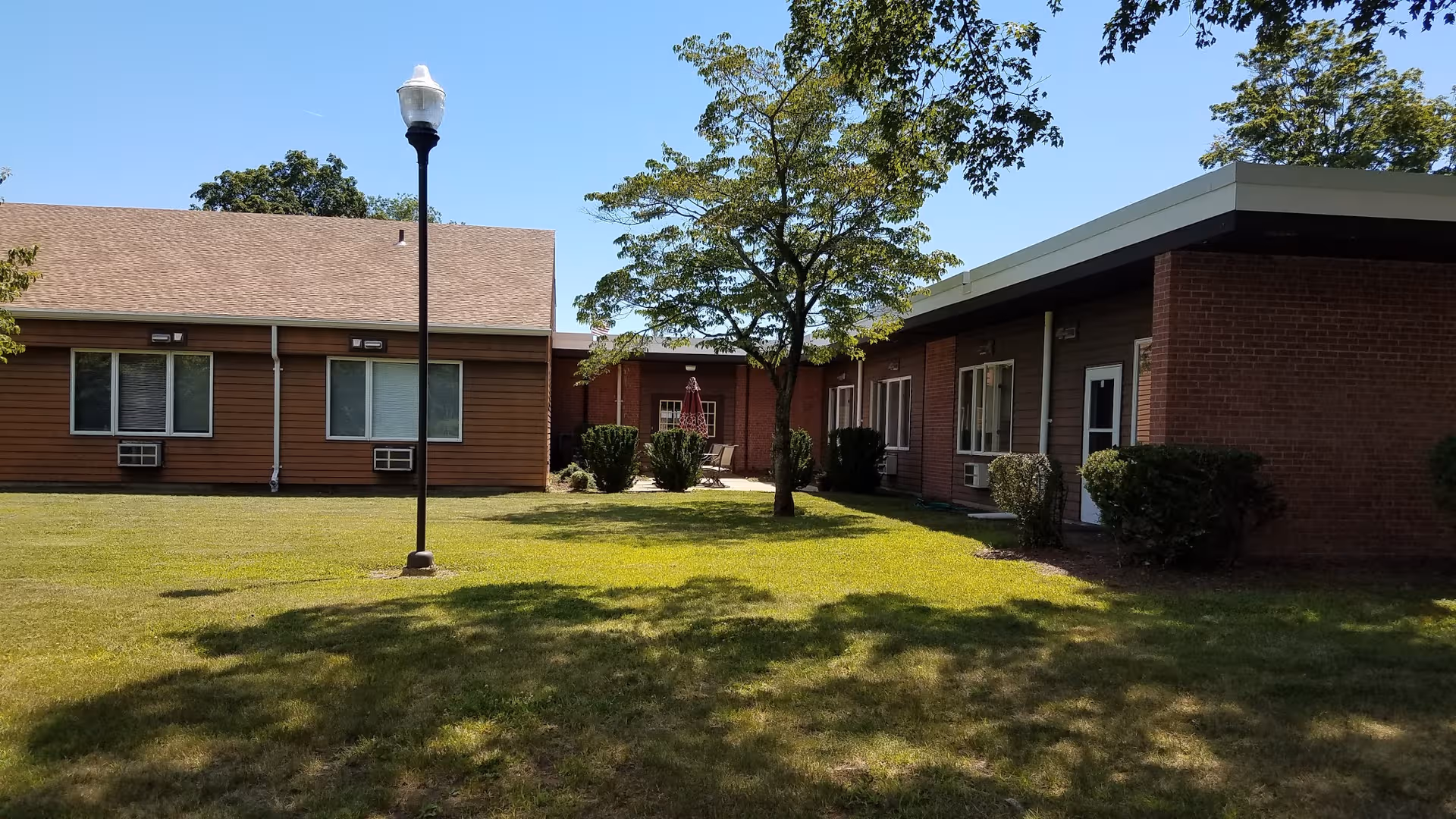 Exterior view of Mt. Carmel Congregate Housing with a grassy courtyard and a tall street lamp.