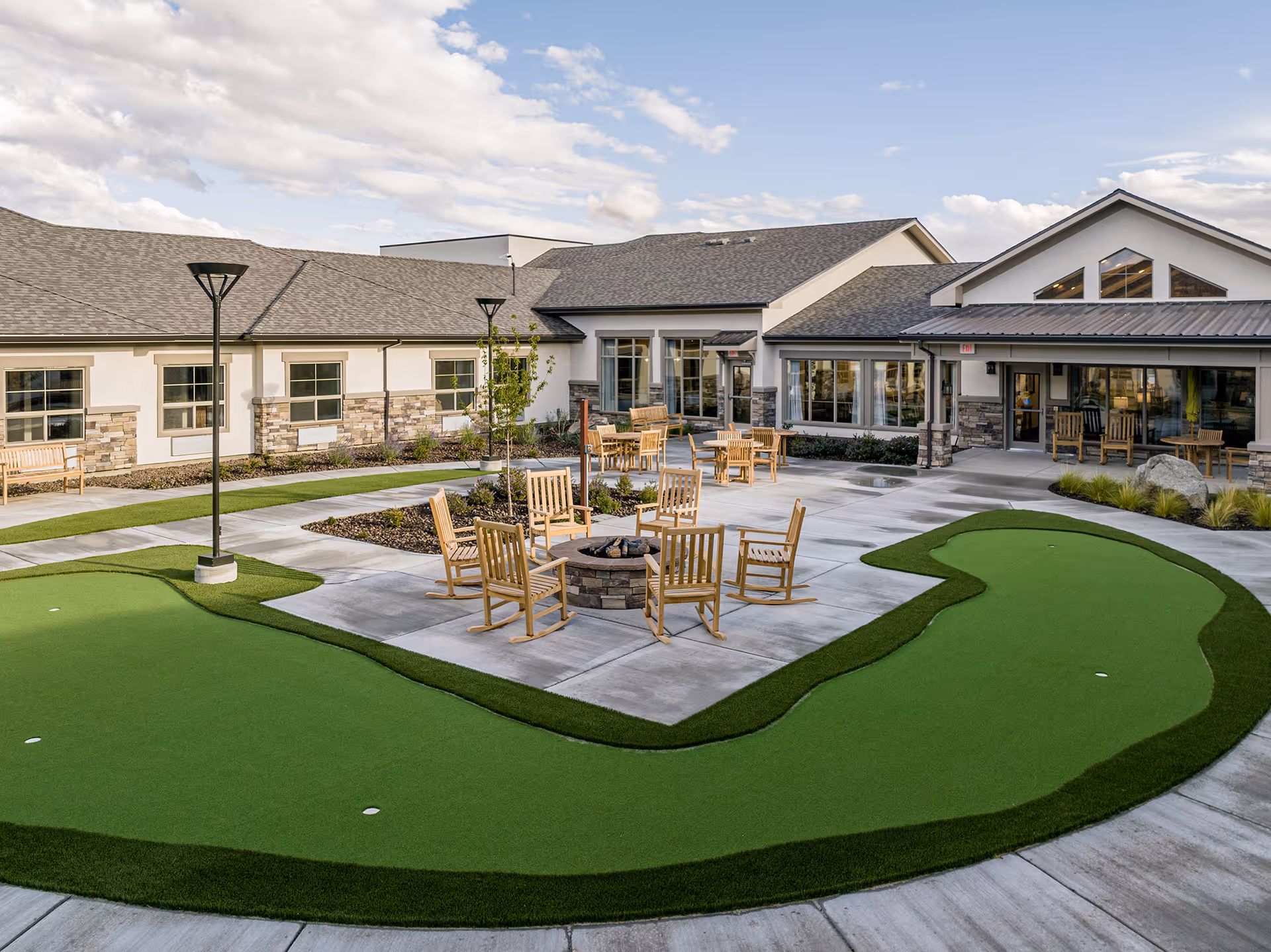 Sage Valley Senior Living outdoor courtyard with a putting green, fire pit, and seating.