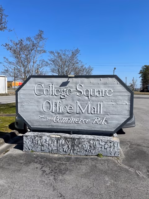 Large stone sign reading College Square Office Mall stands in a parking lot.