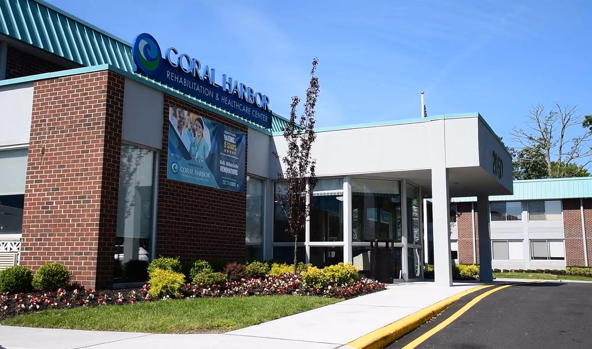Exterior view of Coral Harbor Rehabilitation and Healthcare Center entrance with glass doors and landscaping.