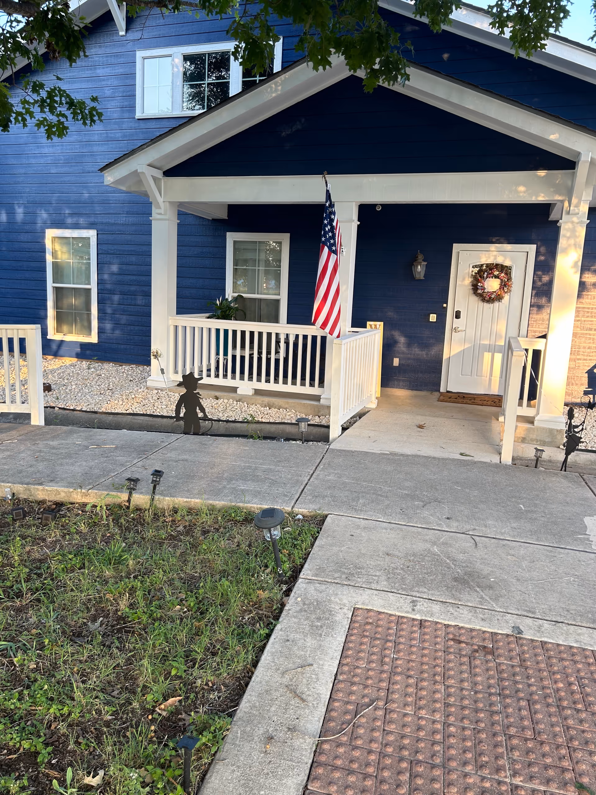 Blue facility exterior with white porch, American flag, wreath on front door.