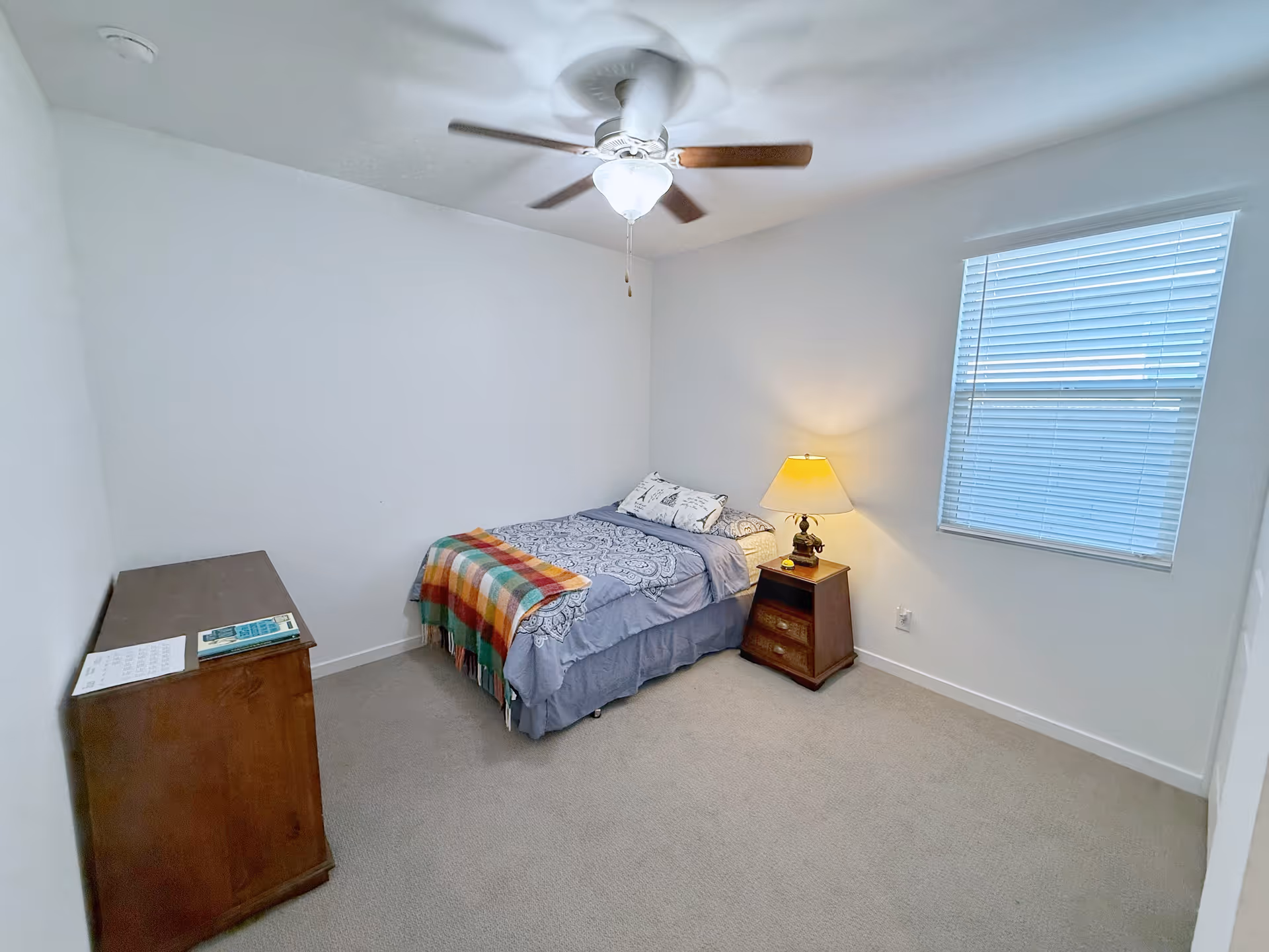 Small bedroom with a bed, nightstand, dresser, ceiling fan, and a window.