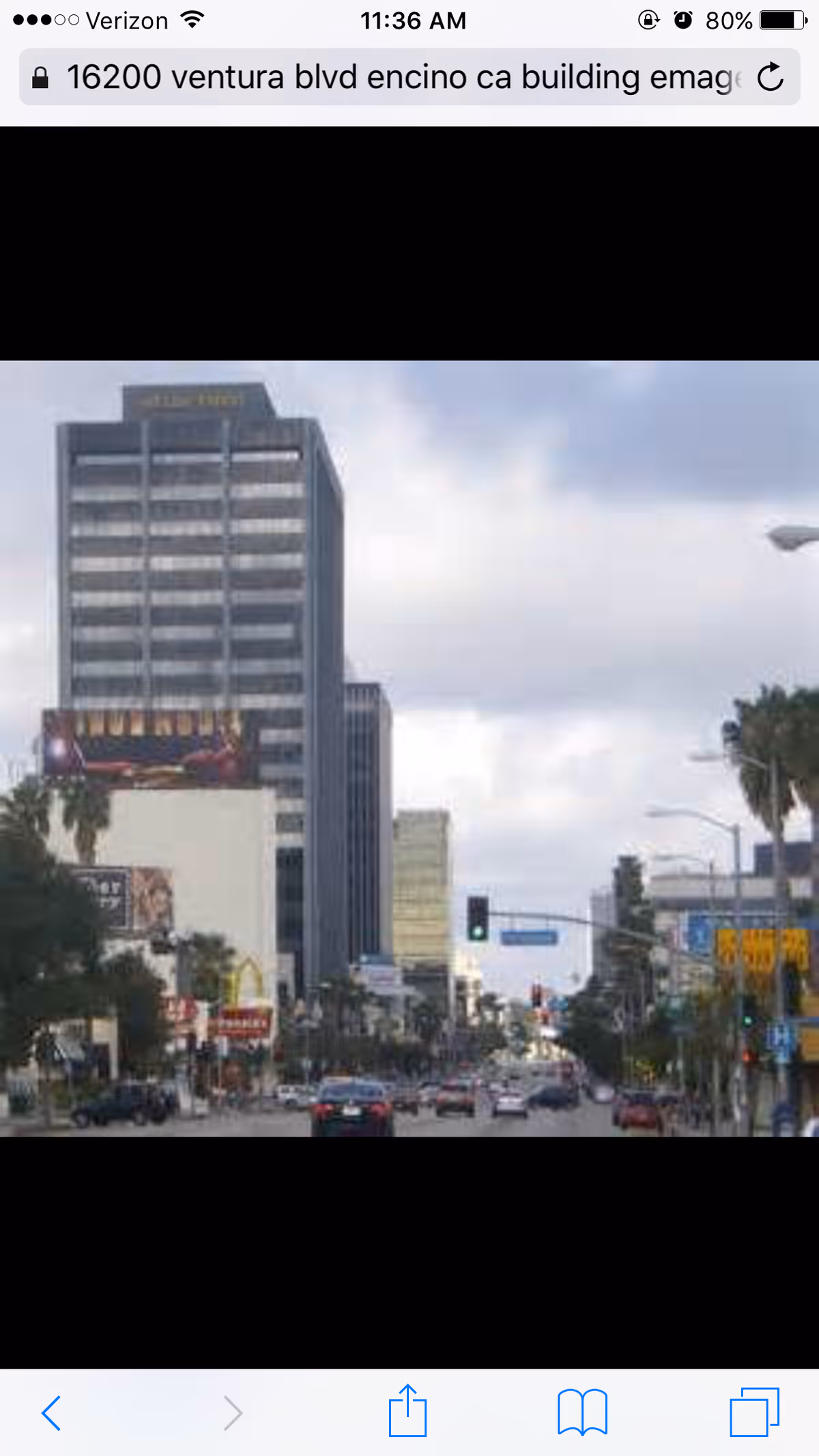 City street with tall office buildings, traffic, and storefronts along the avenue.