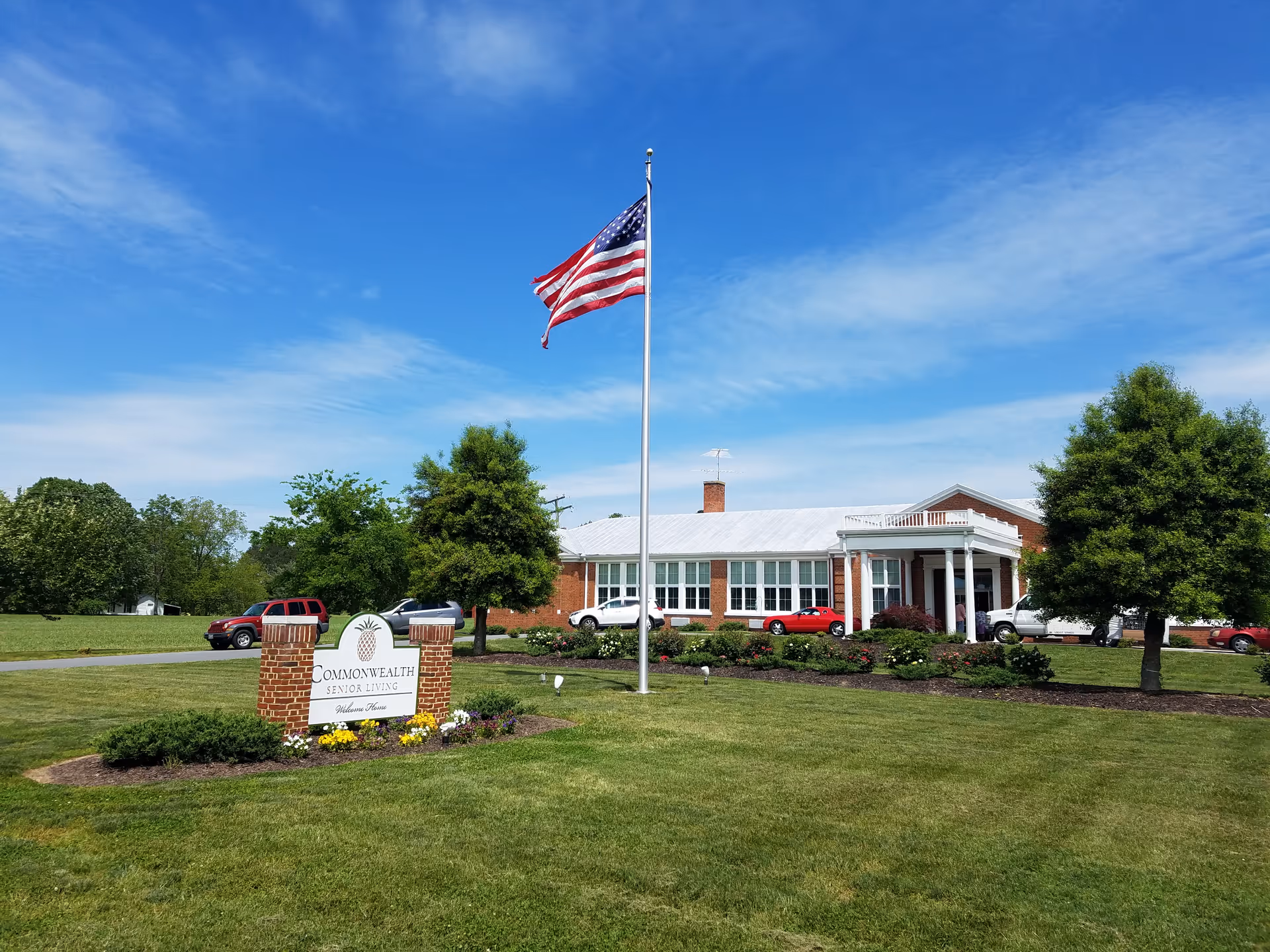 Front view of Commonwealth Senior Living at Farnham with flagpole, lawn, and entrance